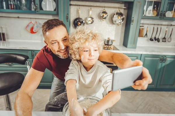 Padre moreno usando su teléfono gris para hacer fotos con su hijo —  Fotos de Stock