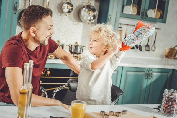 Pai de cabelos escuros sorrindo enquanto observava o filho colocando potholder — Fotografia de Stock