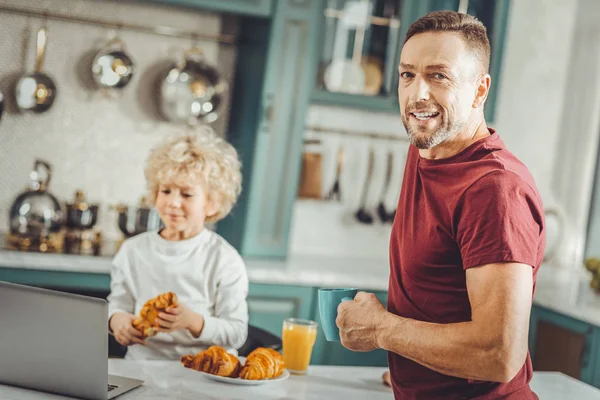 Dark-haired zakenman drinken's ochtends koffie in de buurt van zijn zoon — Stockfoto