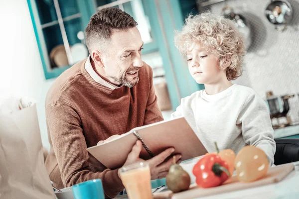 Vrolijke bebaarde man aan te tonen zijn aantekeningen aan zoon — Stockfoto