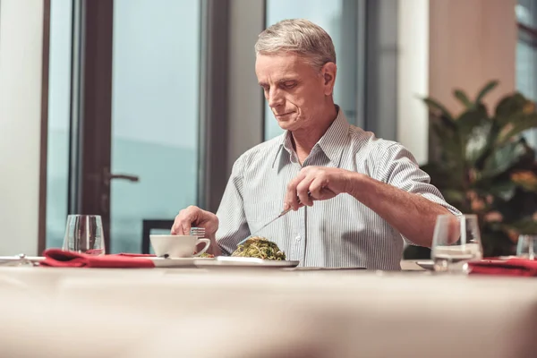 Печальный пенсионер ест салат в ресторане — стоковое фото