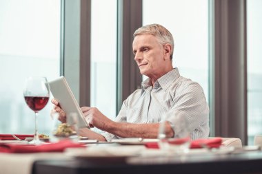 Ciddi emekli öğle yemeği yerken internette arama