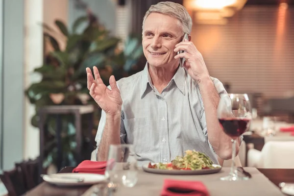 Netter Rentner trinkt Rotwein in einem Restaurant — Stockfoto