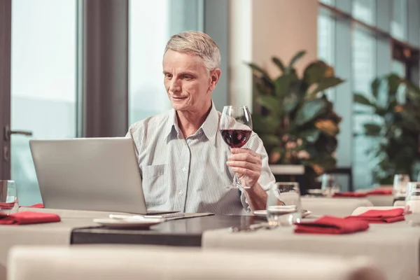 Улыбающийся старик пьет хорошее вино — стоковое фото