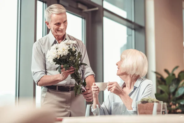 Sorrindo senhora recebendo flores de um homem — Fotografia de Stock