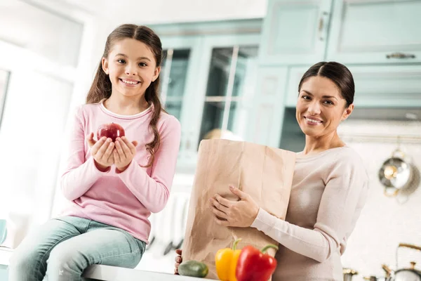 Chica feliz sosteniendo manzana roja en ambas manos — Foto de Stock