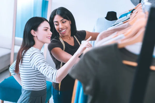 Lachende winkelbediende tonen aan klant nieuwe collectie van kleding — Stockfoto