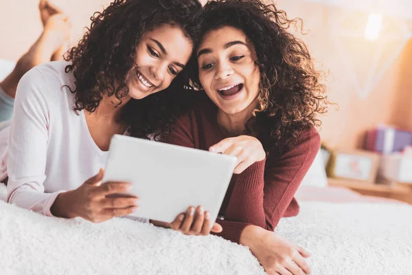 Chicas rizadas riendo mientras miran fotos viejas — Foto de Stock