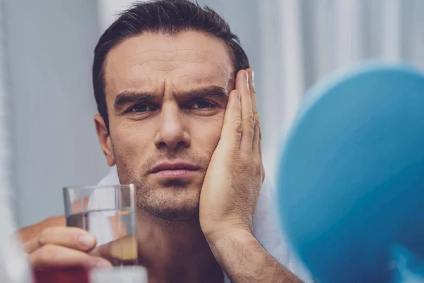 Un bell'uomo con un bicchiere d'acqua in mano — Foto Stock