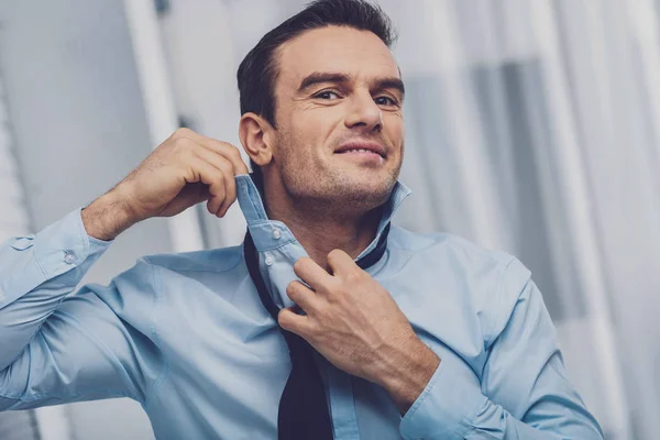 Delighted nice man putting on a tie — Stock Photo, Image