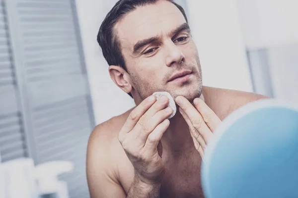 Attentive male person pressing pimples