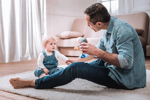 Hombre alegre positivo mostrando un juguete a su hijo — Foto de Stock