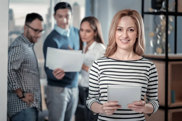 Mujer rubia alegre de pie con su tableta — Foto de Stock