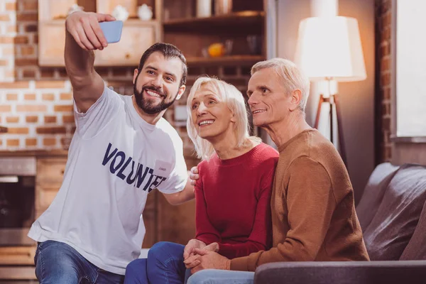 Voluntário feliz selfies com aposentados — Fotografia de Stock