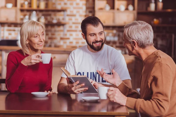 Homem feliz sentado à mesa com aposentados — Fotografia de Stock