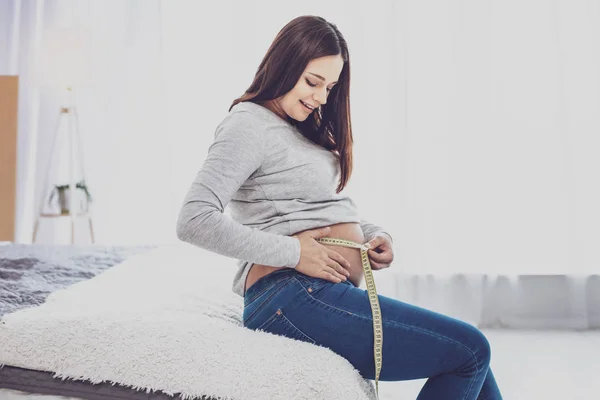 Приятная беременная женщина измеряет свой живот — стоковое фото