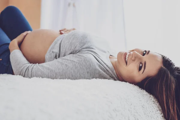 Sevimli hamile kadın yatakta yatarken poz — Stok fotoğraf