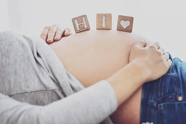 Närbild av gravid kvinna som håller block som säger Hej på buken — Stockfoto
