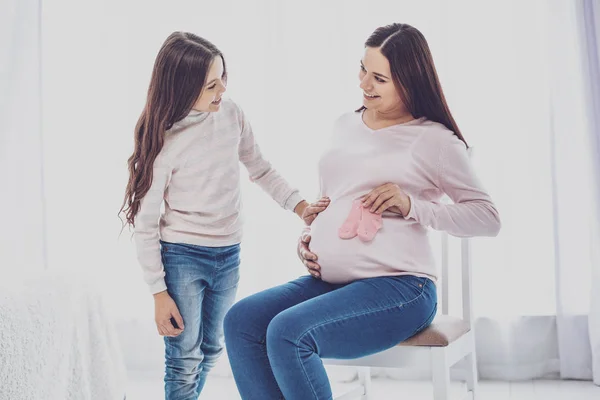 Neşeli kız ve hamile annesi için bebek giyim tartışıyor — Stok fotoğraf