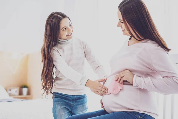 Радісна дев'ятнадцять дівчина питає вагітної матері про дитину — стокове фото