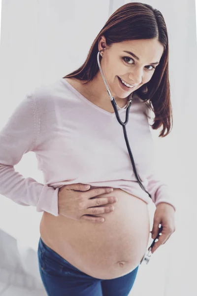 Terhes nő mosolyogva hallgatta a babys szívverés — Stock Fotó