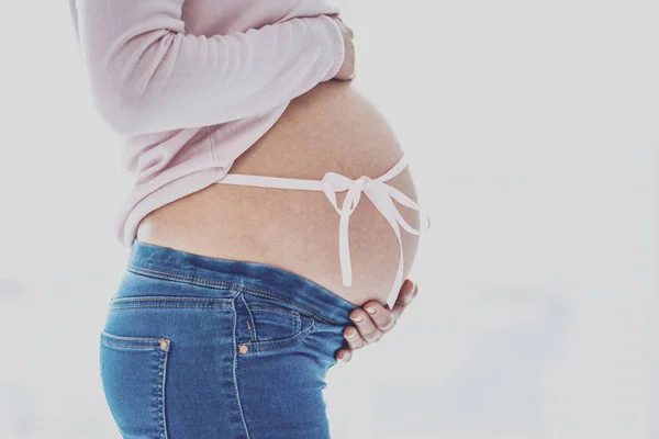 Femme enceinte posant avec un ruban noué autour de son ventre — Photo