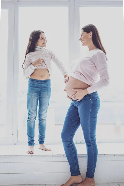 Upbeat little girl touching her pregnant mums belly — Stock Photo, Image
