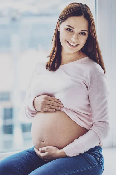 Portrett av en lykkelig, gravid kvinne som poserer med bar mage – stockfoto