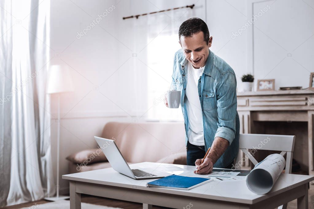 Delighted cheerful man taking notes