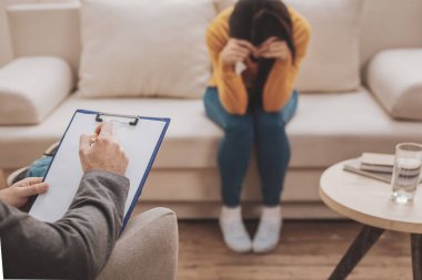 Psikolog istemci önünde oturan koyu gri elbiseli