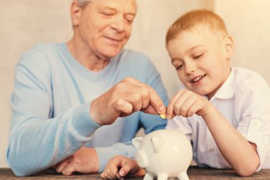 Dede ve torunu sikke para kutusuna koyarak