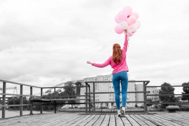Genç kız kendini kadar uzanan pembe balonları tutarken