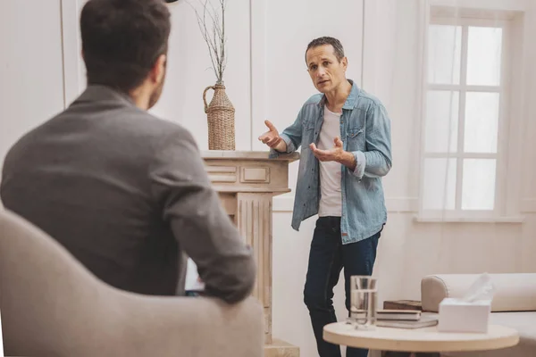 Concerned man wearing white shirt talking to psychologist — Stock Photo, Image