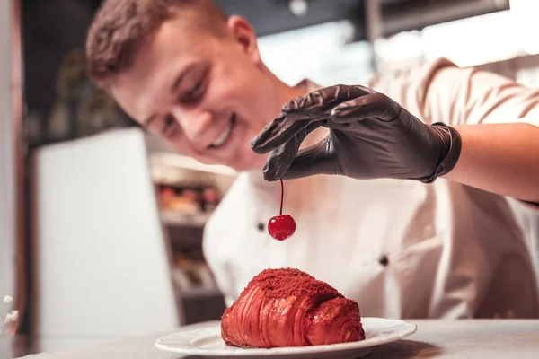 Konditor dekoriert das süße Croissant mit Kirsche — Stockfoto