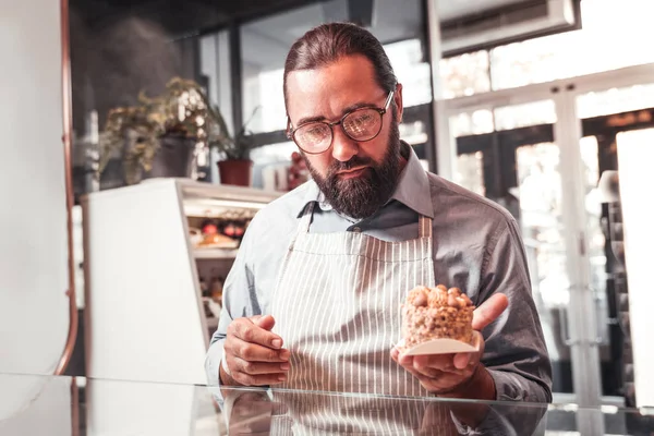 Mann mit Schürze hält leckeren Kuchen in der Hand — Stockfoto