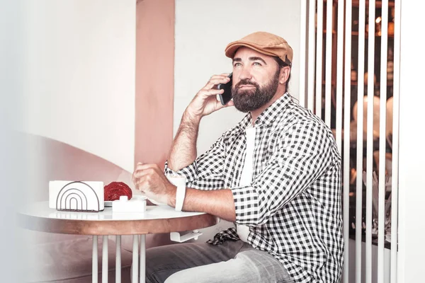 Концентрований чоловік робить телефонний дзвінок, сидячи в каві — стокове фото