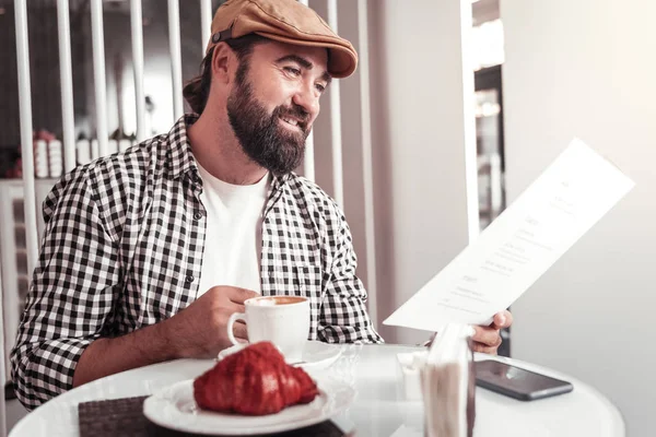 Чоловік дивиться на кавове меню під час пиття кави — стокове фото