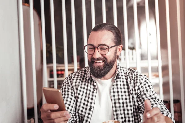 Чоловік використовує смартфон, сидячи в кафе — стокове фото