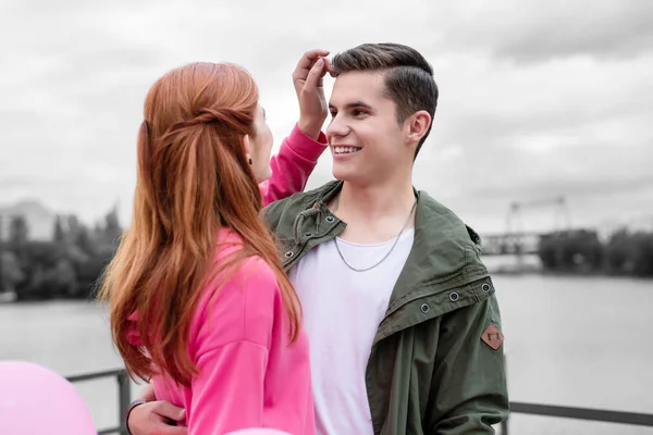 Молодий чоловік посміхається, коли дівчина торкається його волосся — стокове фото