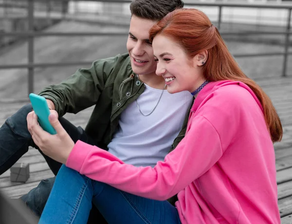 Casal jovem sorrindo enquanto olha para a tela do gadget — Fotografia de Stock