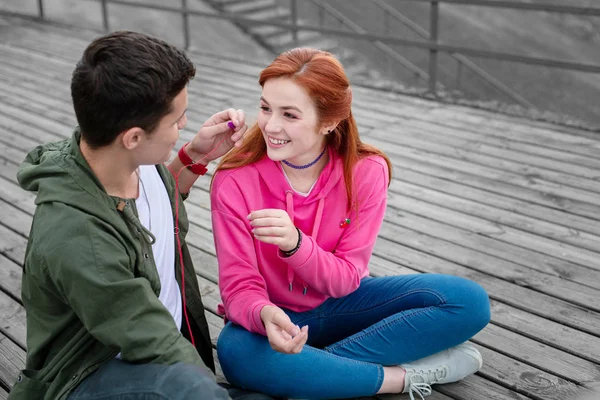 Добрий молодий чоловік дає своїй дівчині навушники і обмінюється музикою — стокове фото