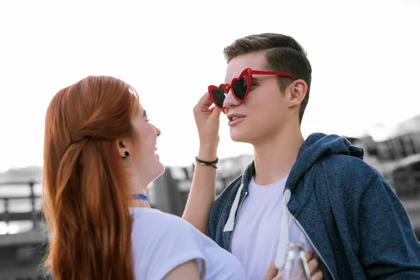 Jovencita riendo mientras le pone gafas graciosas a su novio —  Fotos de Stock