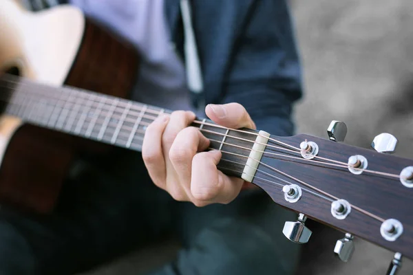 Primer plano del joven con jeans y chaqueta deportiva azul tocando la guitarra — Foto de Stock