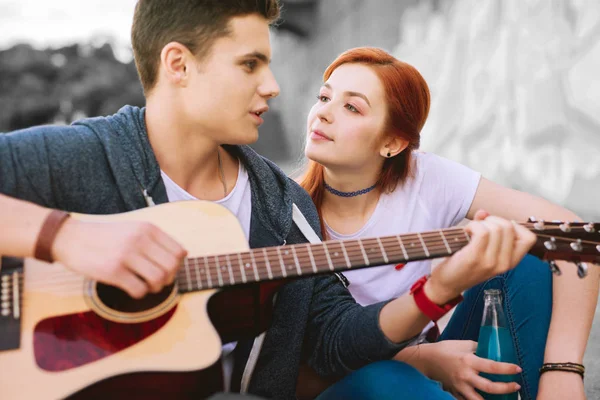 Apelando chica adolescente pelirroja mirando a su novio guapo con guitarra —  Fotos de Stock