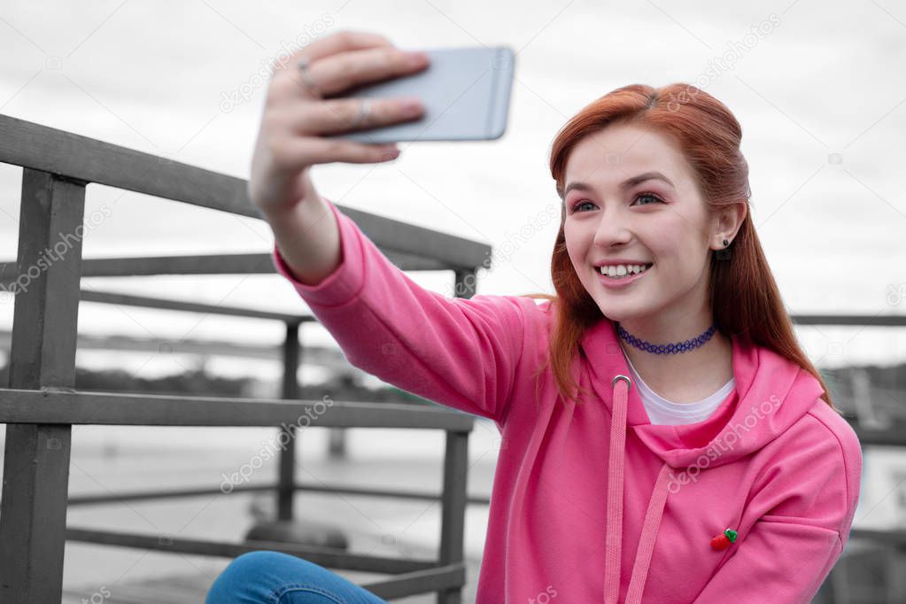 Pretty young girl smiling and taking selfies alone