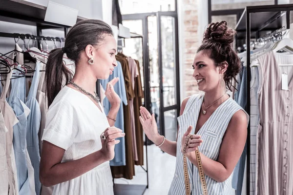 Fashion designer with tape measure in her hands giving consultation her visitor