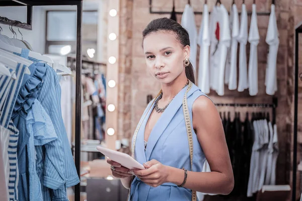 Busy hard-working fashion designer having tape measure on her neck