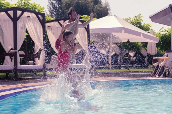 Feliz linda chica saltando con sus padres en el agua — Foto de Stock