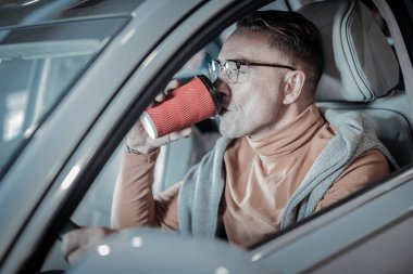 Şık işadamı araba sürüş sırasında kahve içme