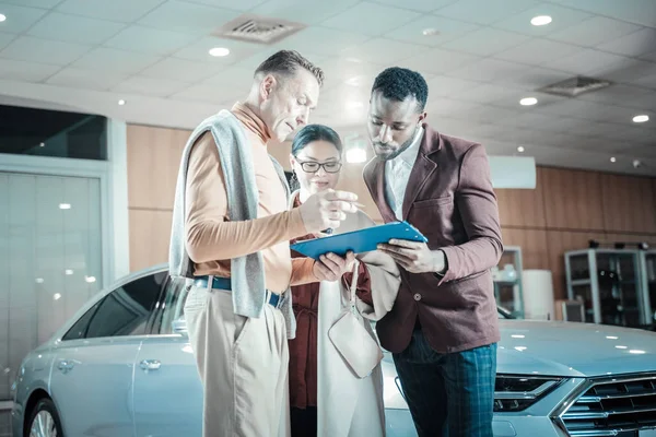 Man klädd i beige byxor underteckna dokument för försäkring av bil — Stockfoto